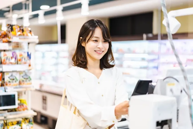 レジで嬉しそうにスマホ決済をする若い女性