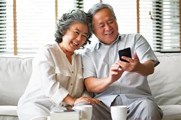 笑顔でスマートフォンを操作するご年配夫婦の画像